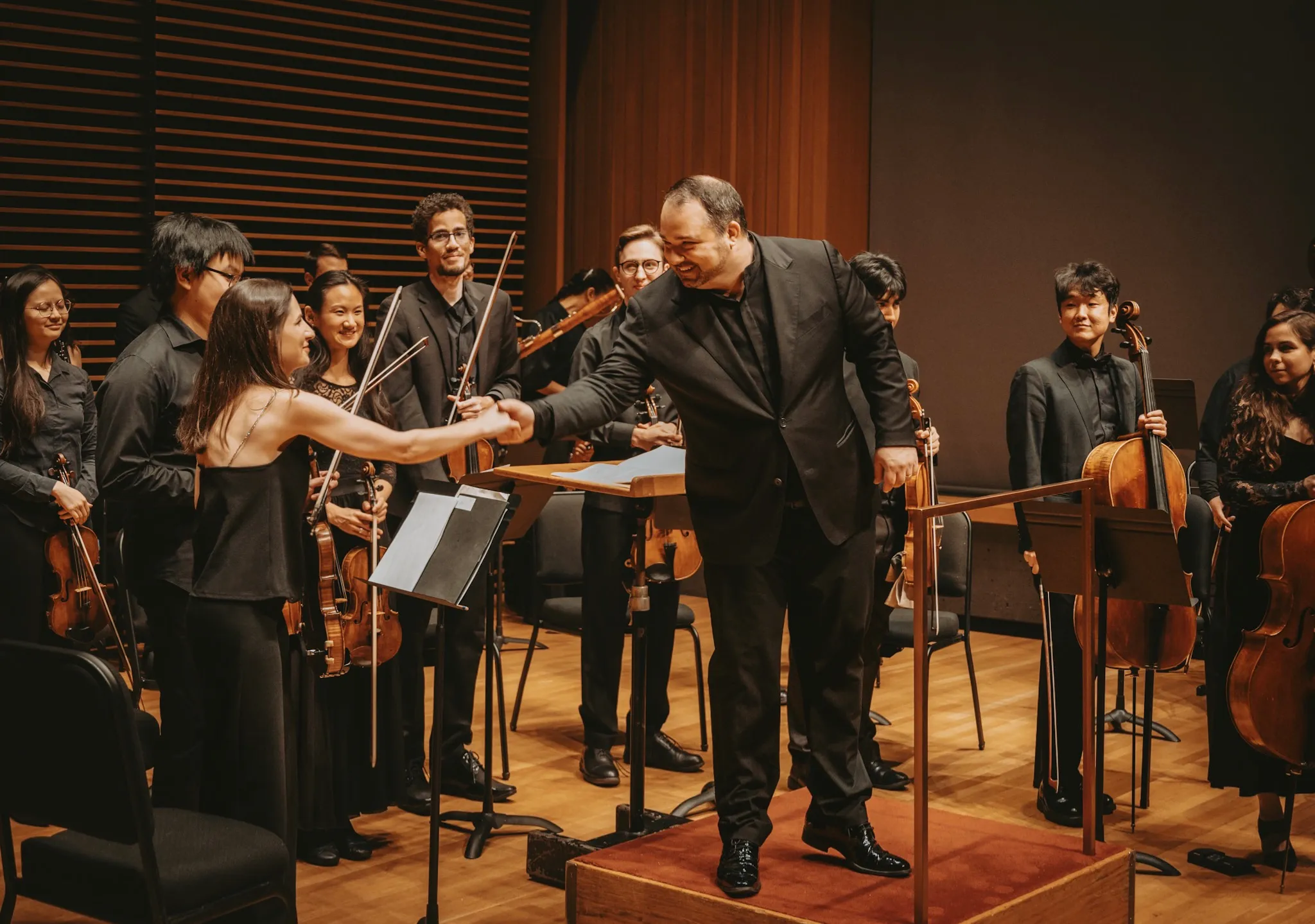 Tatev Muradyan as concertmaster of the Chicago ensemble Intermezzi, shaking hands with principal conductor Leo Radosavljevich.